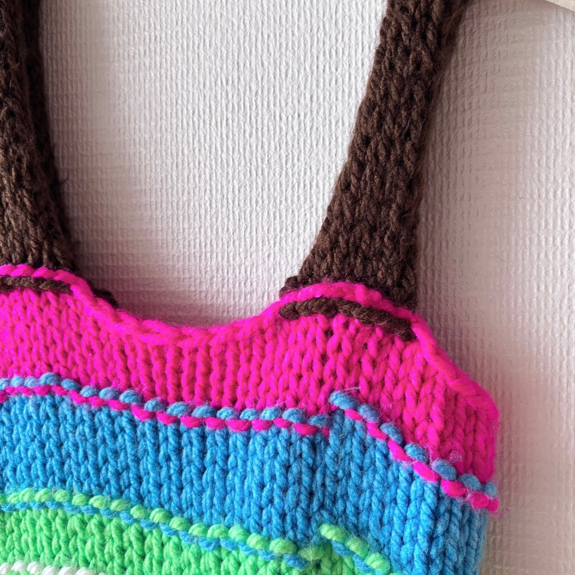 Close-up of handmade shoulder straps on the colorful knit dress, highlighting textured knit and detailing