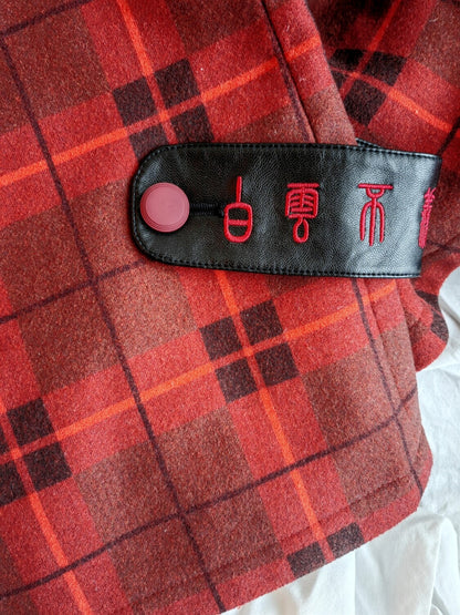 Close-up view of a black leather strap with red embroidered characters on Dark red thick bell bottom pants